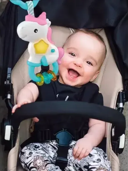 Neonato sorridente con un gioco Baby Clementoni